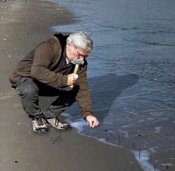 Guy Hammering Nails Into Sand meme template